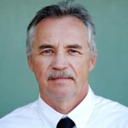 Older man with dark hair, gray at the temples, and a salt-and-pepper mustache